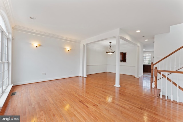 unfurnished living room featuring ornamental molding, light wood finished floors, stairway, and visible vents