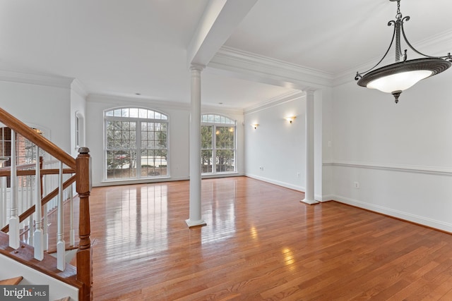 unfurnished living room with decorative columns, stairway, and wood finished floors