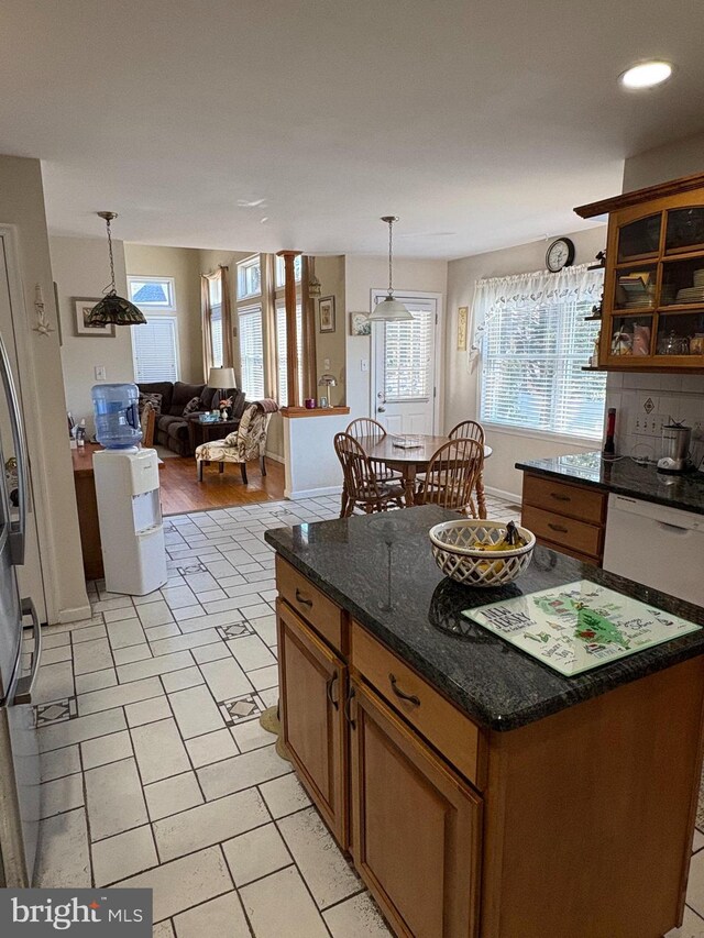 kitchen featuring white dishwasher, a kitchen island, hanging light fixtures, brown cabinets, and tasteful backsplash