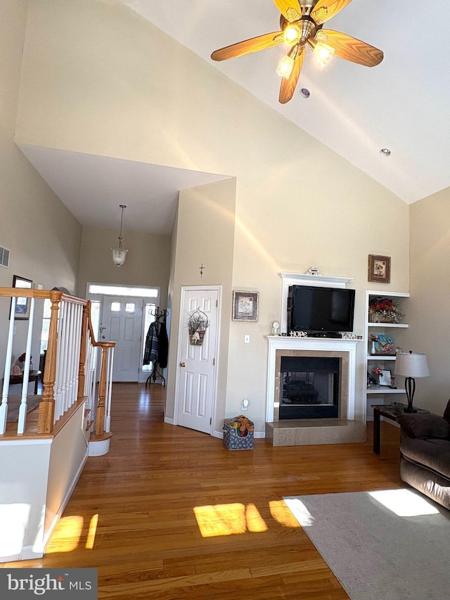 living room with stairs, high vaulted ceiling, and wood finished floors