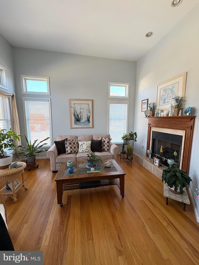 living room featuring light wood-style floors, a fireplace, and a high ceiling