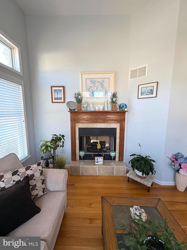 living area with baseboards, visible vents, wood finished floors, and a tile fireplace