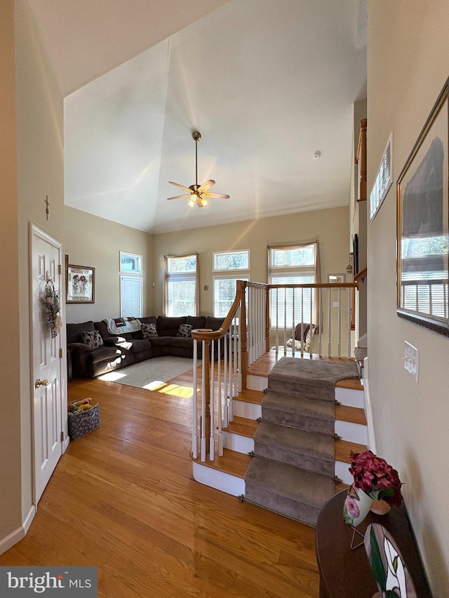 stairs with plenty of natural light, wood finished floors, and a ceiling fan