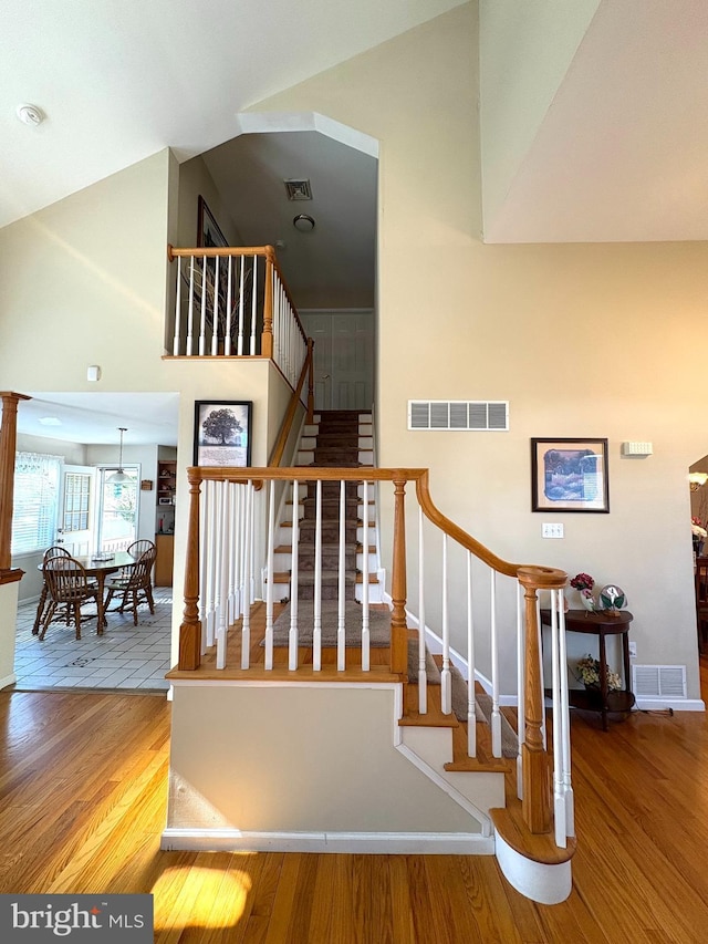 stairs featuring lofted ceiling, wood finished floors, visible vents, and baseboards