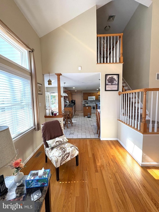 interior space with high vaulted ceiling, visible vents, stairway, and light wood finished floors