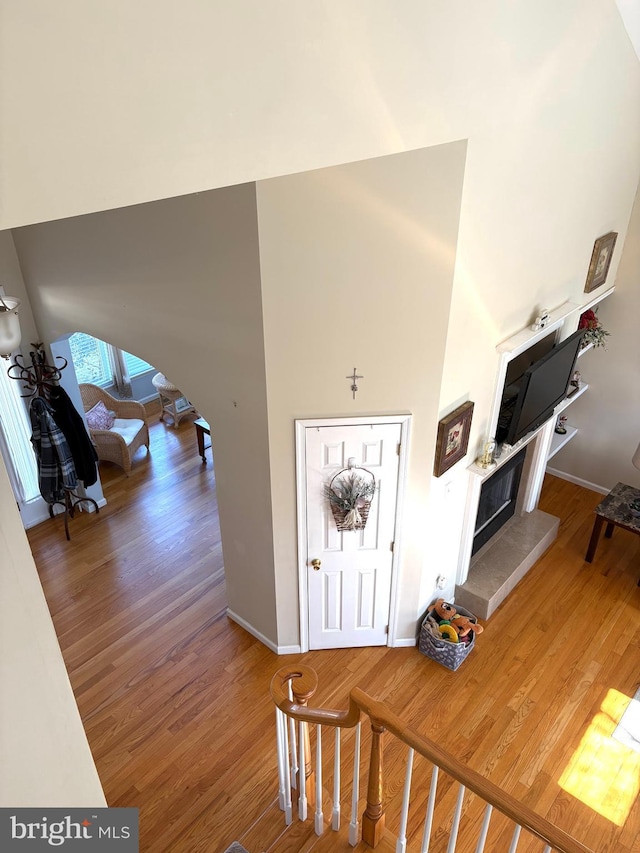 entrance foyer featuring arched walkways, a high ceiling, wood finished floors, and baseboards