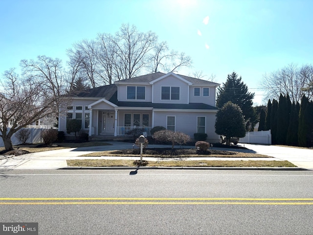 traditional home featuring driveway, a porch, and fence