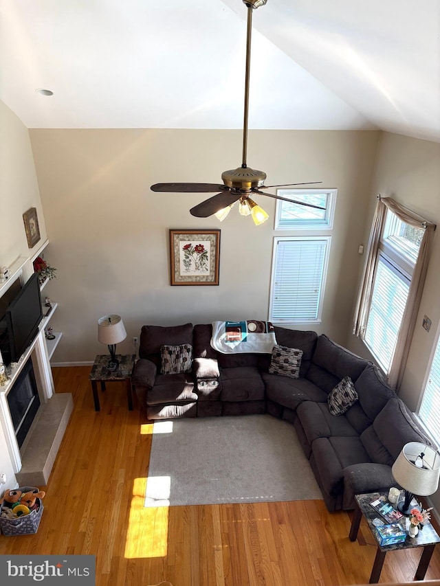 unfurnished living room featuring a ceiling fan, a fireplace with raised hearth, and light wood finished floors