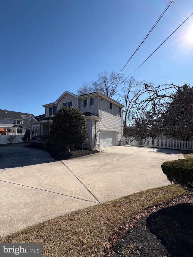 view of side of property featuring driveway, a garage, and fence