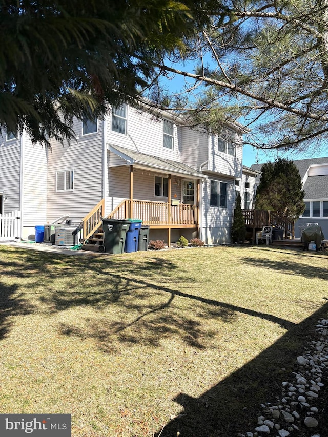 back of property with a wooden deck and a yard