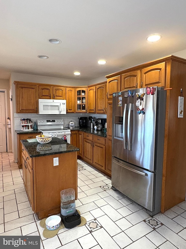 kitchen with white appliances, a kitchen island, brown cabinets, tasteful backsplash, and glass insert cabinets