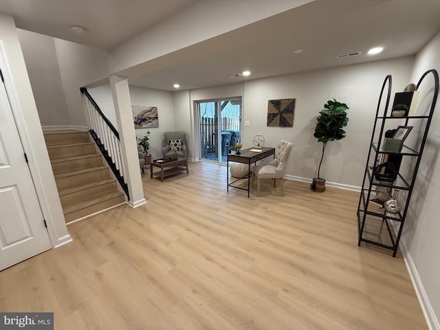 living area featuring light wood-type flooring, baseboards, stairs, and visible vents