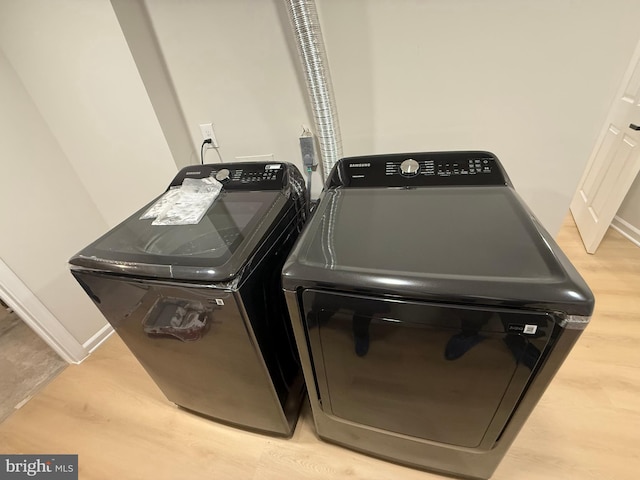 clothes washing area with washer and dryer, laundry area, baseboards, and light wood finished floors