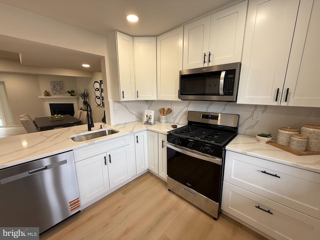 kitchen featuring appliances with stainless steel finishes, a sink, and light stone counters