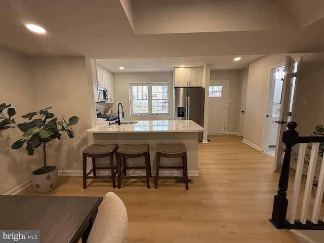 kitchen featuring a peninsula, appliances with stainless steel finishes, a sink, and white cabinets