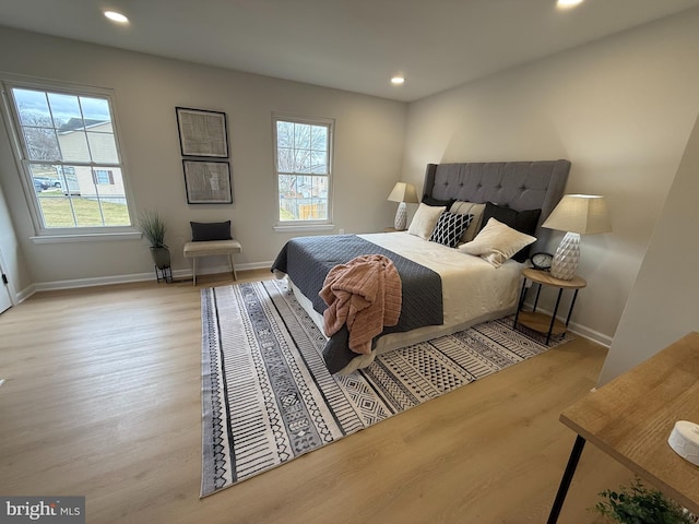 bedroom with multiple windows, baseboards, and wood finished floors