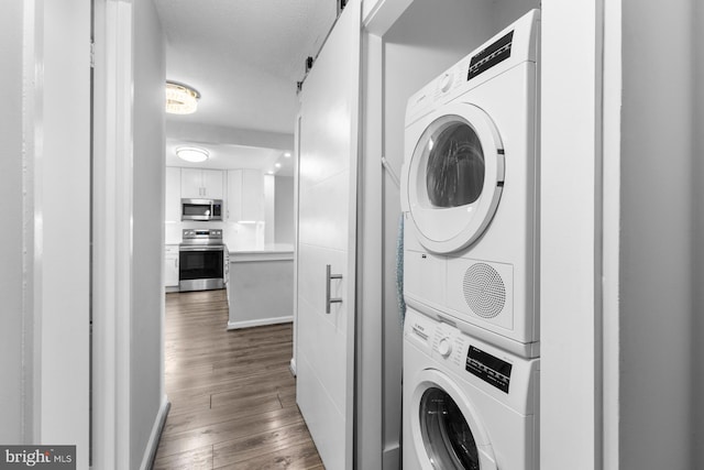 laundry area with stacked washer and clothes dryer, baseboards, a textured ceiling, and dark wood-style flooring