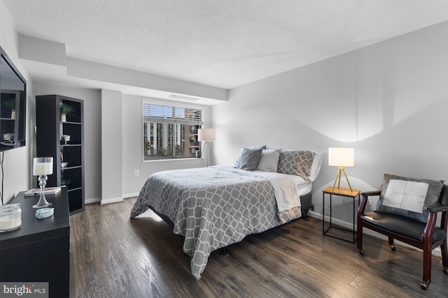 bedroom with a textured ceiling, baseboards, and wood finished floors