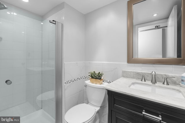 full bath with toilet, a shower stall, tile walls, and vanity