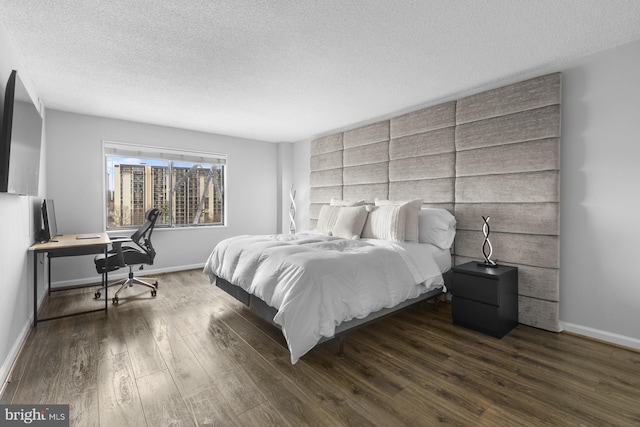 bedroom with a textured ceiling, baseboards, and wood finished floors