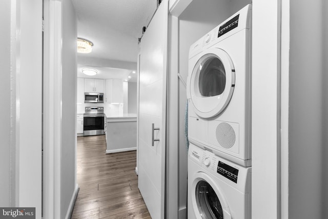 clothes washing area with dark wood-type flooring, stacked washer and clothes dryer, and a textured ceiling