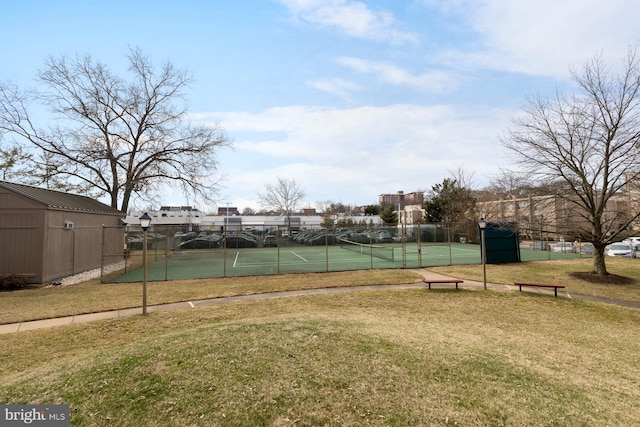 view of tennis court featuring fence and a yard