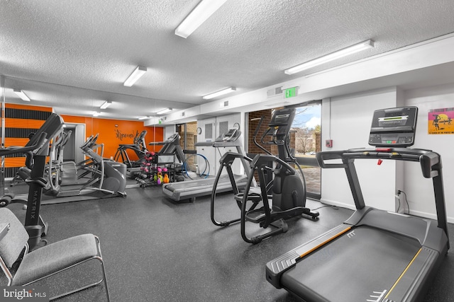 exercise room with a textured ceiling, visible vents, and baseboards