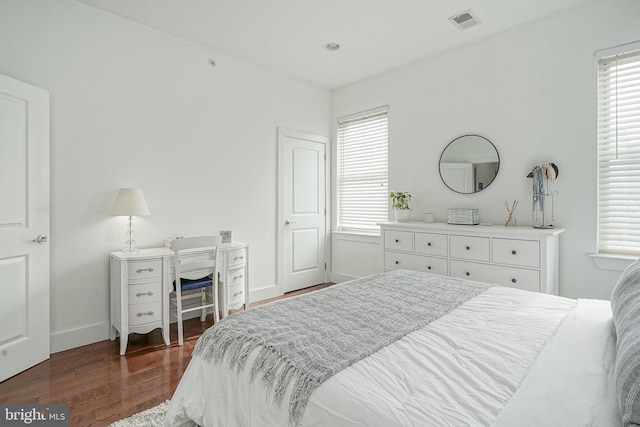 bedroom with baseboards, multiple windows, visible vents, and dark wood-style flooring