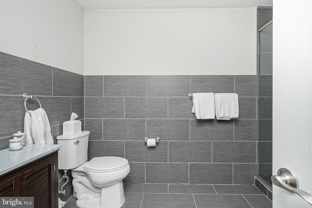 full bathroom featuring vanity, tile walls, toilet, and walk in shower