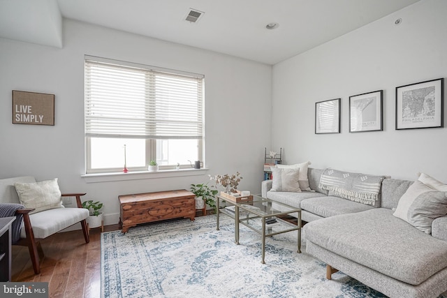 living room with visible vents, baseboards, and wood finished floors