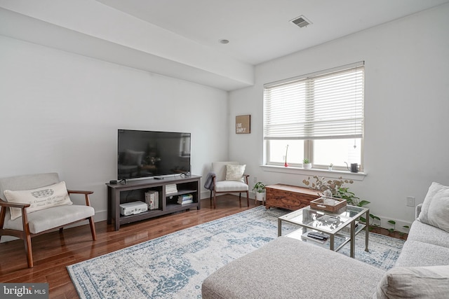 living room featuring wood finished floors, visible vents, and baseboards