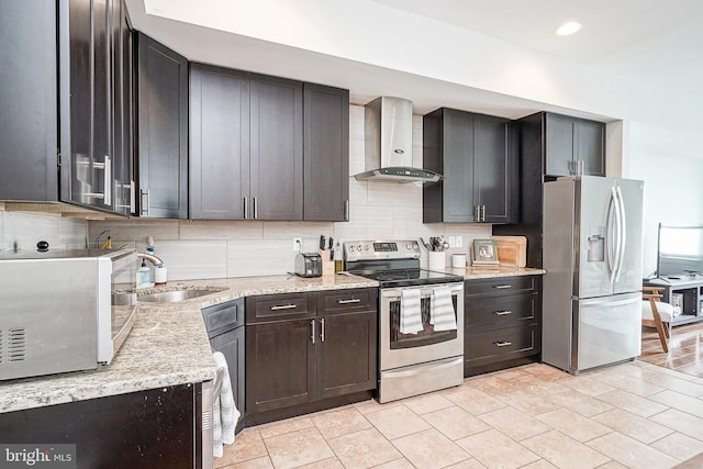 kitchen with stainless steel appliances, a sink, wall chimney exhaust hood, and tasteful backsplash