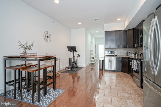 kitchen with baseboards, visible vents, decorative backsplash, stainless steel appliances, and recessed lighting