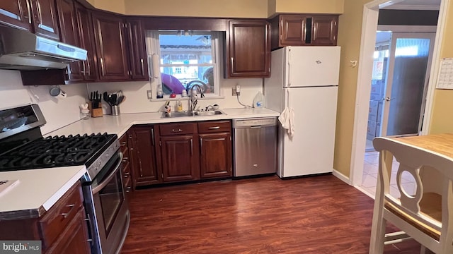 kitchen with dark wood-style flooring, light countertops, appliances with stainless steel finishes, a sink, and under cabinet range hood