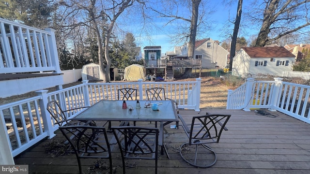 wooden deck with an outbuilding, outdoor dining area, fence, and a shed