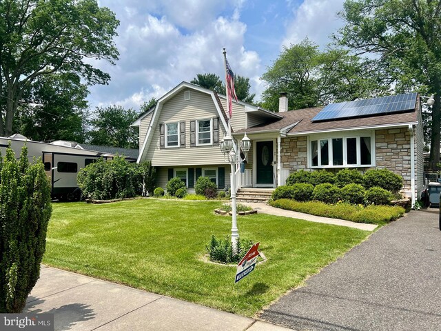 44 Tantum Dr, Hamilton, NJ 08610 - tri-level home with stone siding, roof mounted solar panels, a front yard, a gambrel roof, and a shingled roof