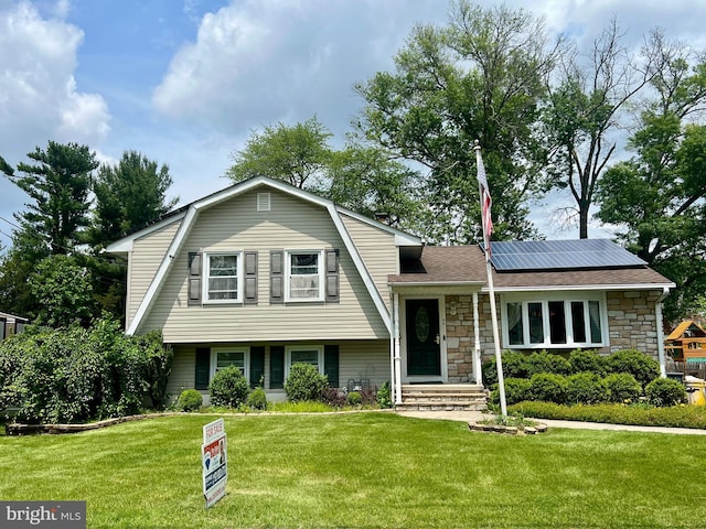 44 Tantum Dr, Hamilton, NJ 08610 - split level home with roof mounted solar panels, stone siding, a front lawn, a gambrel roof, and roof with shingles