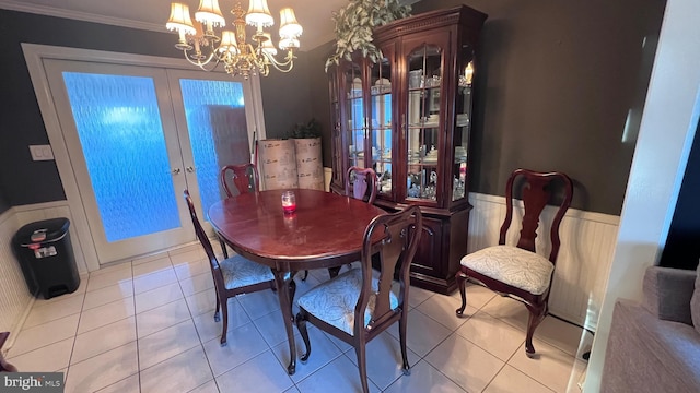 dining room featuring french doors, wainscoting, crown molding, and light tile patterned flooring