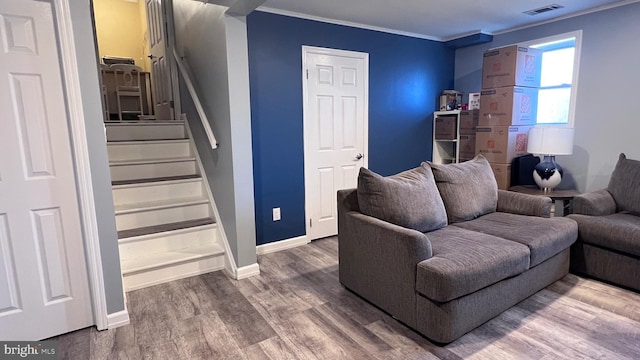 living area with wood finished floors, visible vents, baseboards, ornamental molding, and stairway