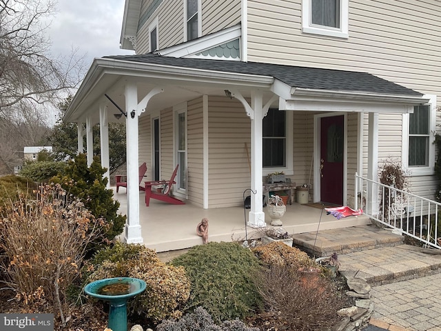 property entrance with covered porch and roof with shingles