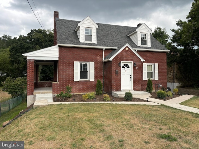 cape cod house featuring brick siding, a front lawn, a shingled roof, and fence