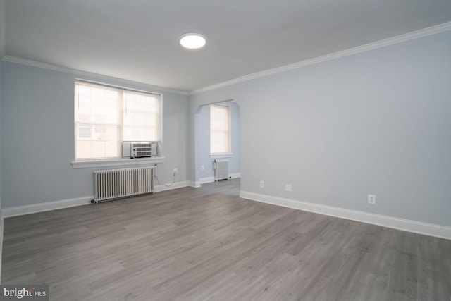 spare room with radiator, crown molding, and wood finished floors