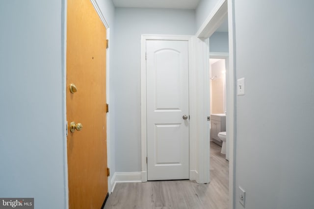 hall featuring light wood-style floors and baseboards