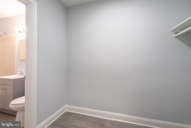 bathroom with toilet, baseboards, wood finished floors, and vanity