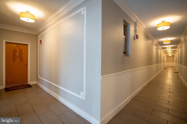 hallway featuring baseboards, wood finish floors, and crown molding