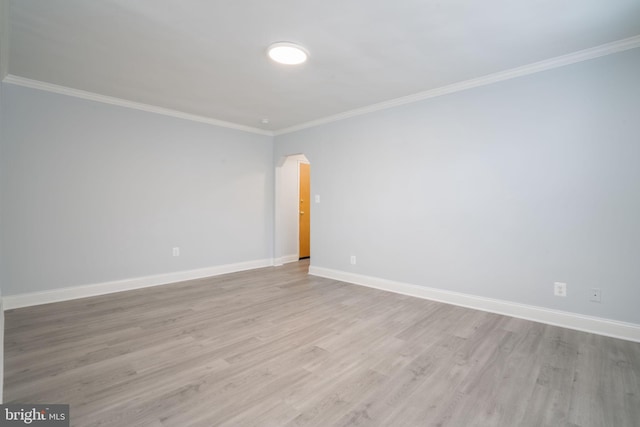 unfurnished room with light wood-type flooring, arched walkways, ornamental molding, and baseboards