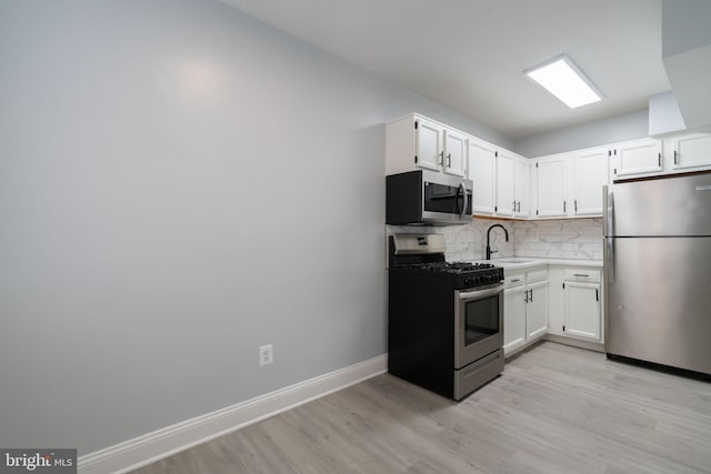 kitchen with white cabinets, appliances with stainless steel finishes, backsplash, and a sink