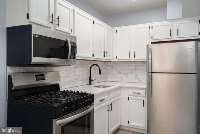 kitchen featuring stainless steel appliances, white cabinets, a sink, and decorative backsplash