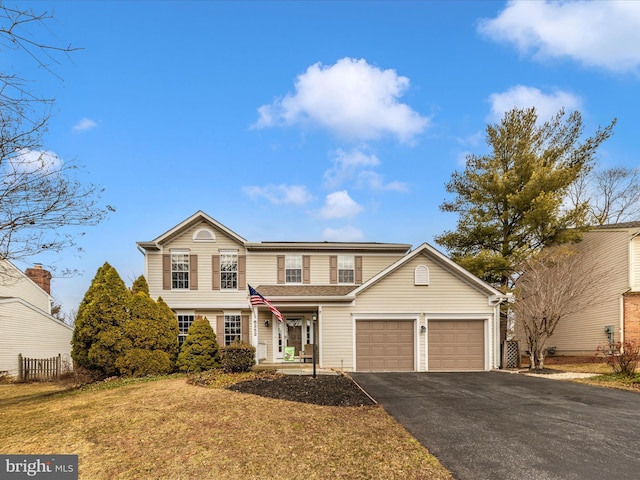 traditional home featuring an attached garage, aphalt driveway, and a front yard