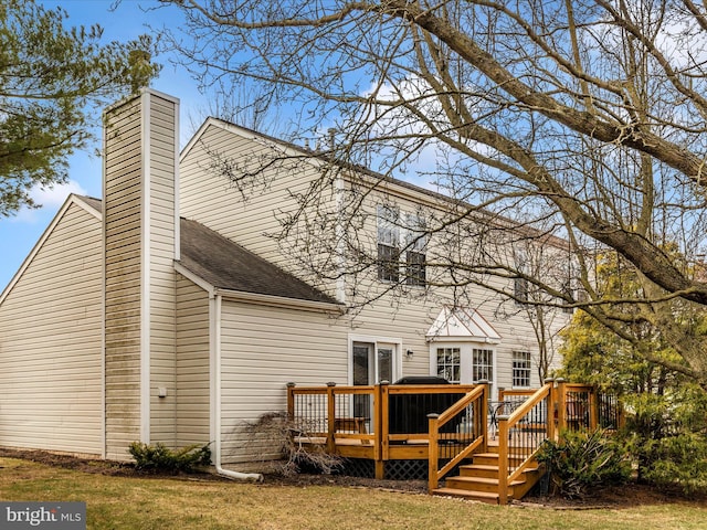 rear view of house featuring roof with shingles, a chimney, and a wooden deck